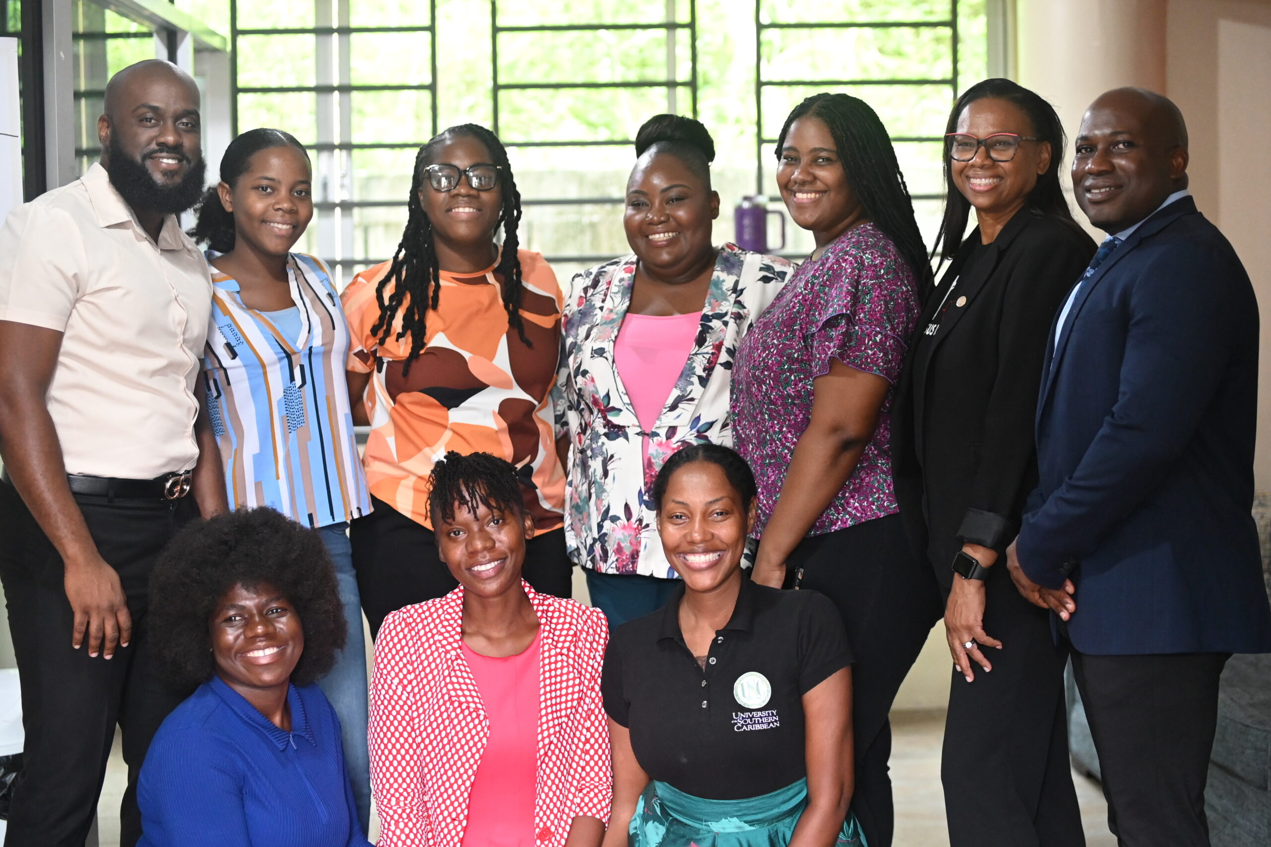 A group photograph of University of the Southern Caribbean (USC) staff and students smiling together indoors. The group features Mr Dominic Merritt (Dean of Men, Timothy Greaves Residence Hall), Student Dean Ms Edira Eugene, Ms Starlene Peters (Dean of Women, Ladies Residence Hall), Resident Assistant Ms Zarrah Toussaint, Chaplain Rachel Sealy, and Pr Terry John (VP of Spiritual Development), alongside several female students standing and seated in the front