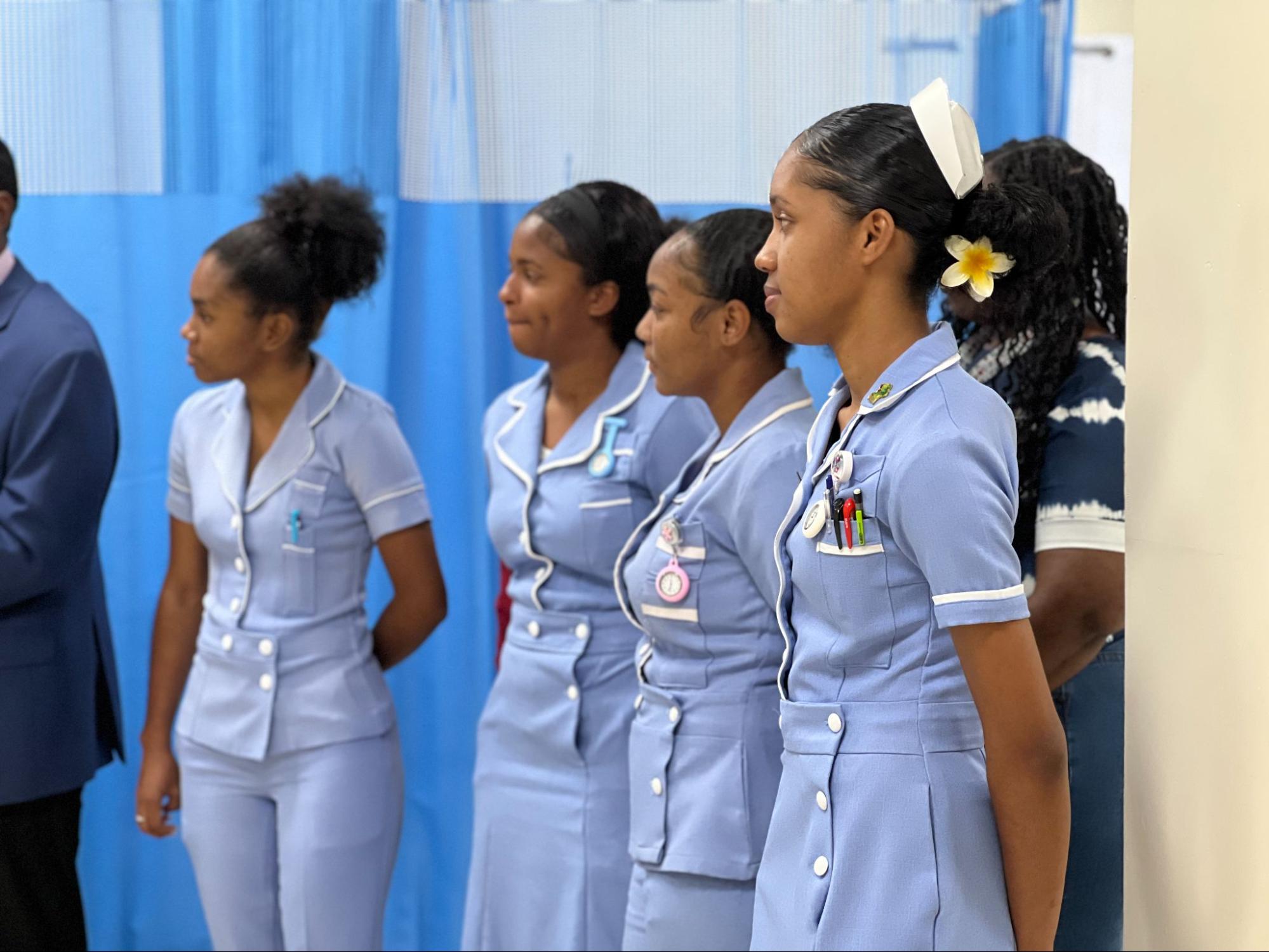 A line of female nursing students in light blue uniforms standing attentively in the new skills lab