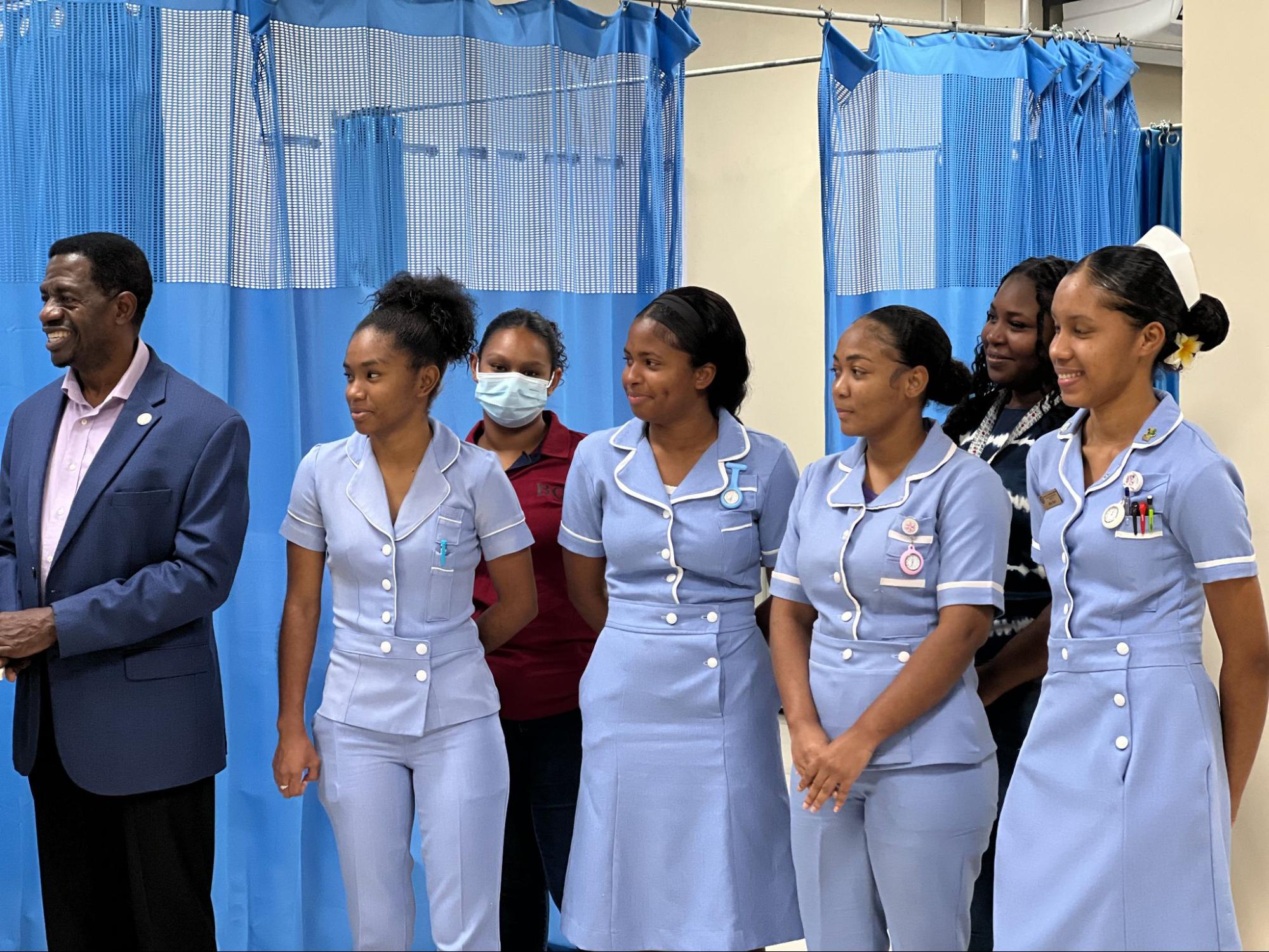 USC President Dr. Wilson smiling proudly alongside a group of female nursing students in their light blue clinical uniforms