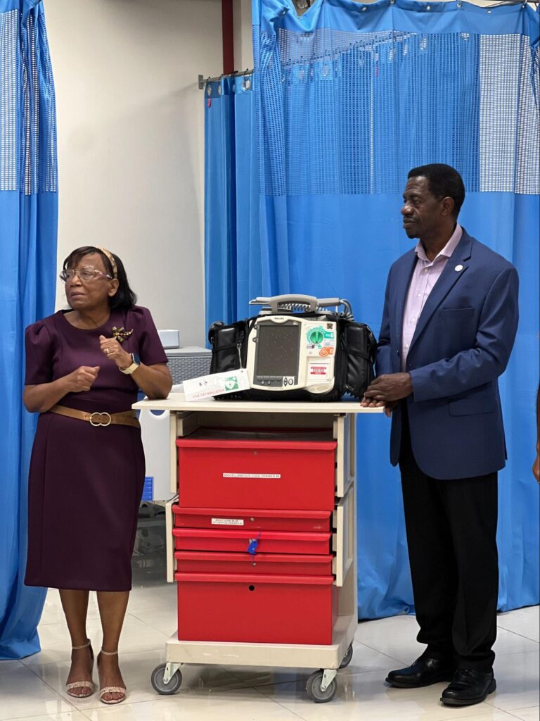 Dr. Phyllis Woolford and Dr. Wilson standing next to a red clinical cart equipped with a Philip defibrillator