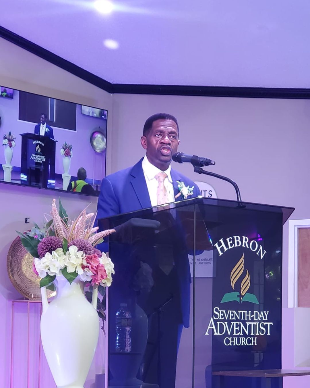 University of the Southern Caribbean President Dr. Colwick Wilson stands at a wooden podium delivering a sermon at Hebron Seventh-day Adventist Church during the inaugural USC Texas Alumni Chapter weekend.