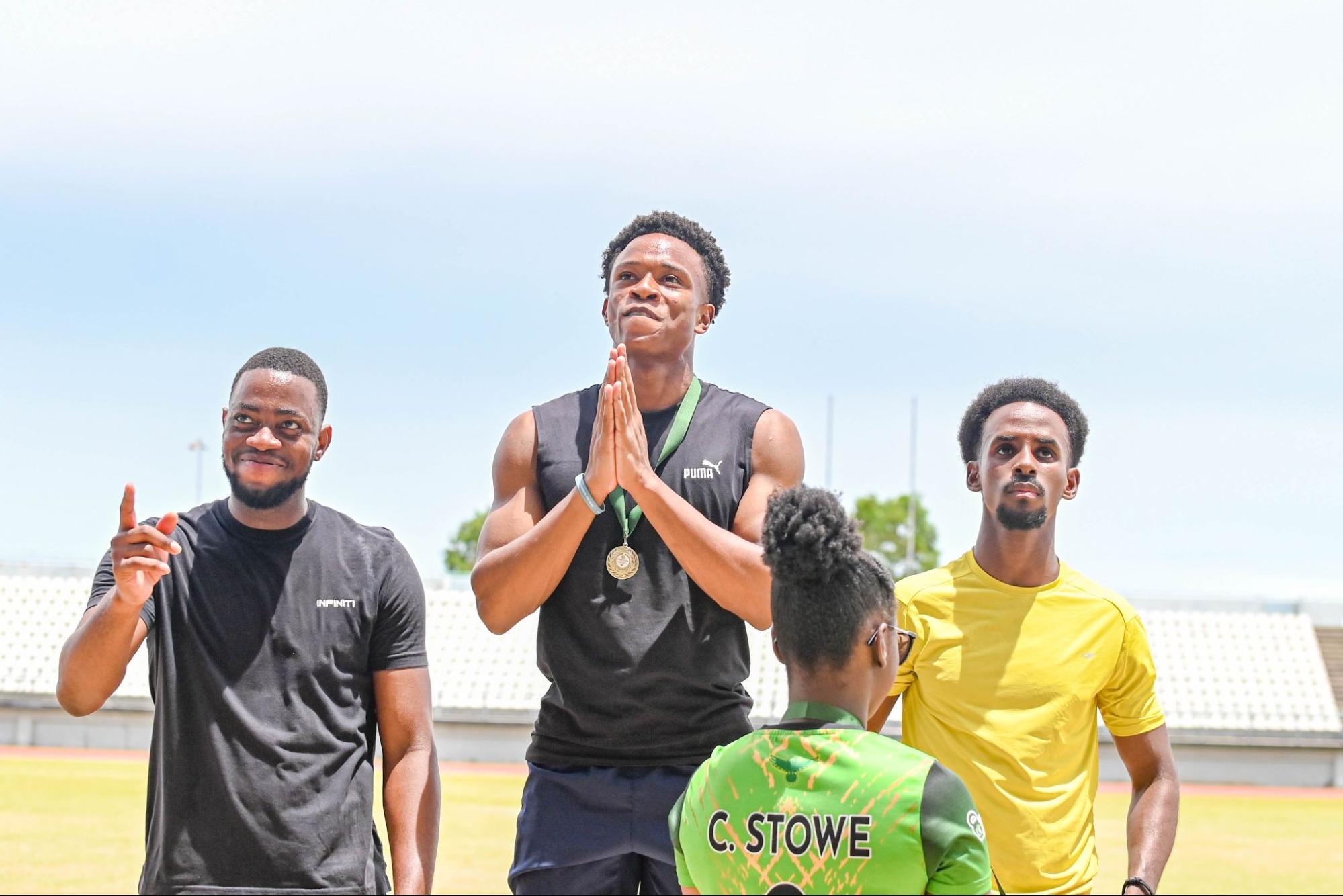 Eron Jack with hands in prayer on a podium