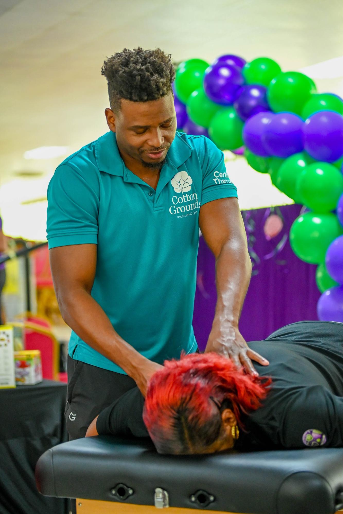 A male therapist from Cotton Ground Institute & Spa provides a complimentary back massage to a woman at a University of the Southern Caribbean AOK-100 community health fair.