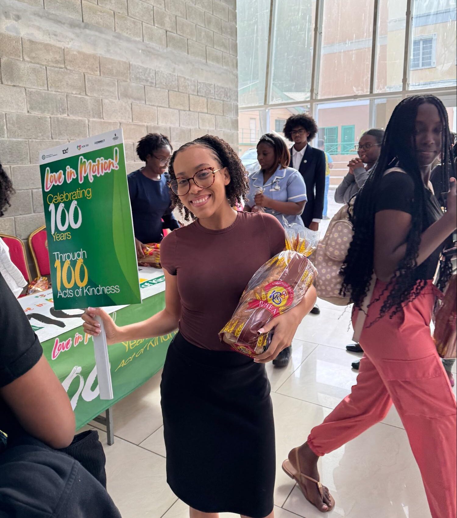 Students from the University of the Southern Caribbean receiving fresh bread during the Associated Student Body's 'Love in a Loaf' charity drive, part of the AOK-100 centennial community outreach.