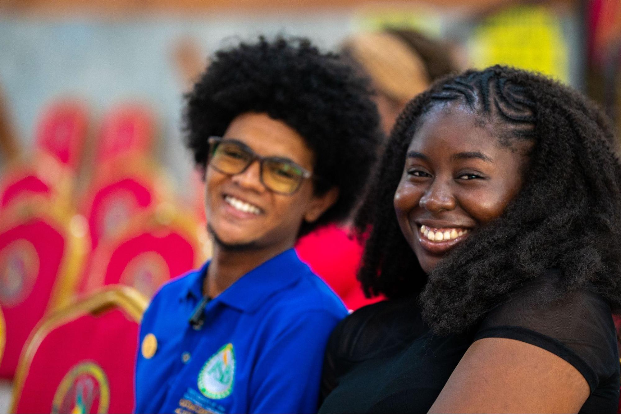A man in a blue ASB polo and a woman in a black top smiling at the camera while seated in the audience.