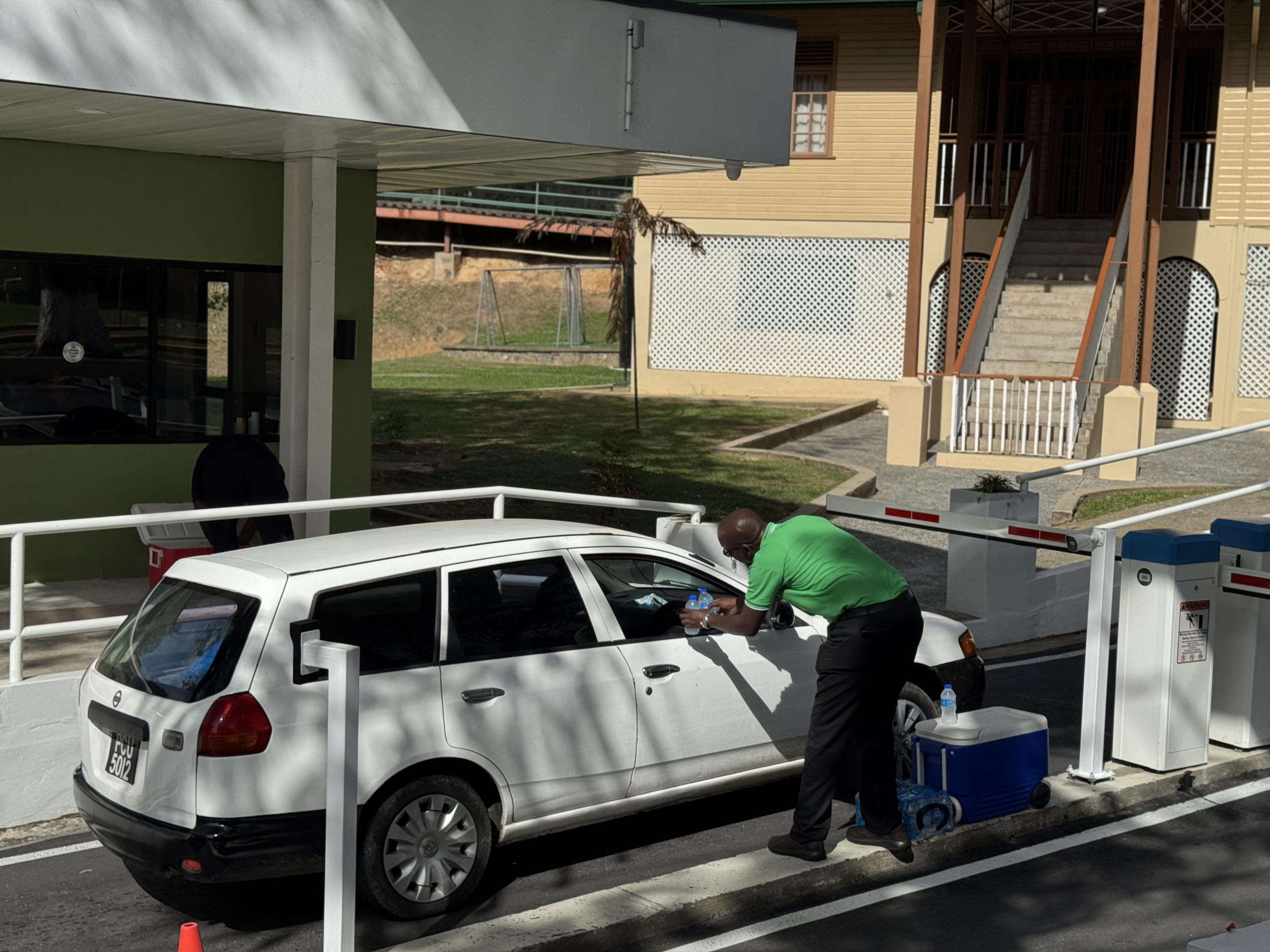 A USC staff member in a green shirt distributing bottled water to a driver in a white vehicle on campus.