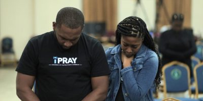 University of the Southern Caribbean students participating in Week of Prayer. The image shows two young adults in a solemn prayer moment at the USC campus.